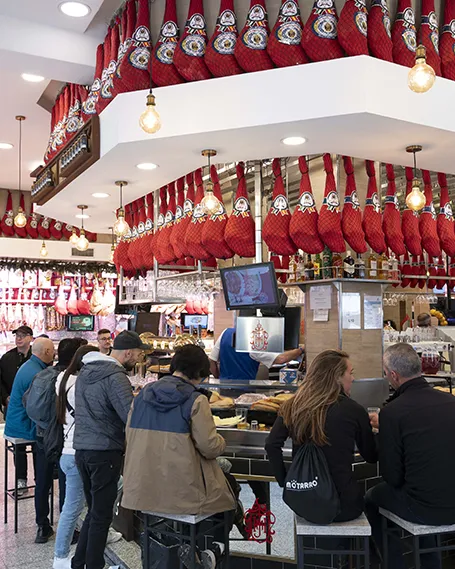 Clientes disfrutando en la barra del Museo del Jamón en la Carrera de San Jerónimo, Madrid