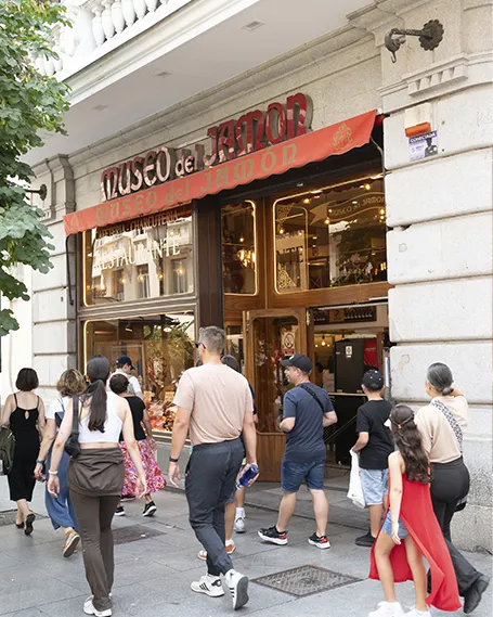 Exterior del Museo del Jamón en la Calle Mayor, Madrid, con un grupo de personas entrando al establecimiento