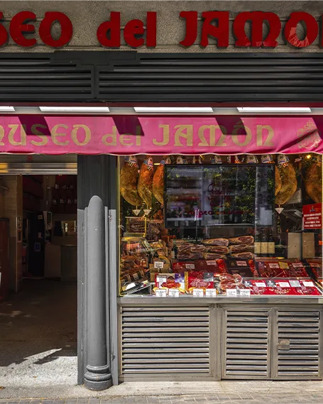Fachada del Museo del Jamón en el Paseo del Prado, Madrid, con jamones expuestos en el escaparate.