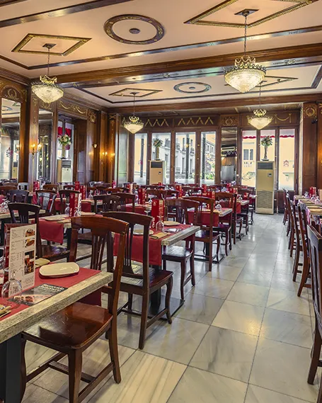 Salón interior del Museo del Jamón en la Calle Mayor, Madrid, con mesas elegantemente dispuestas y decoración clásica