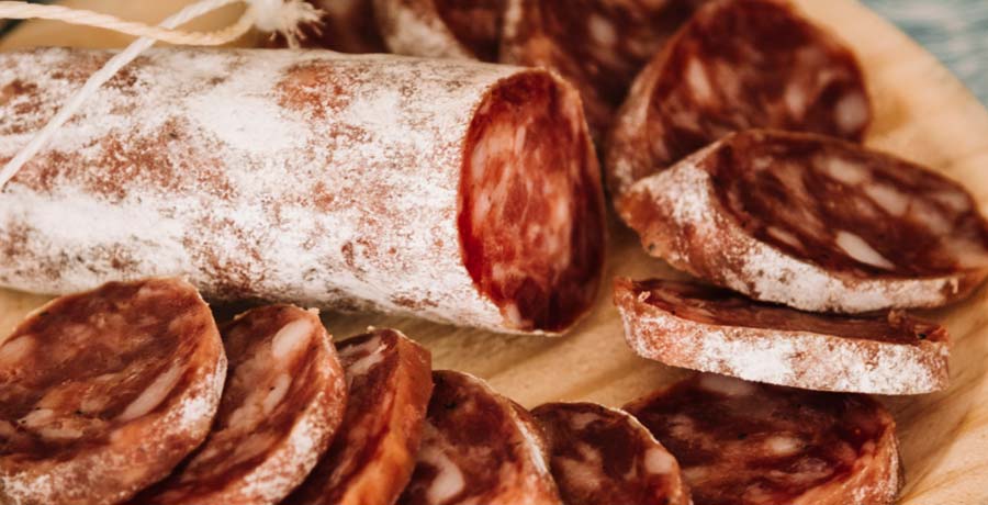 Lonchas de chorizo ibérico de bellota cortado sobre tabla de madera en el Museo del Jamón